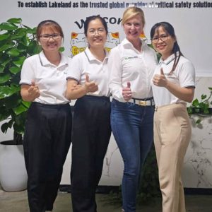 Four people smiling in front of Lakeland sign.