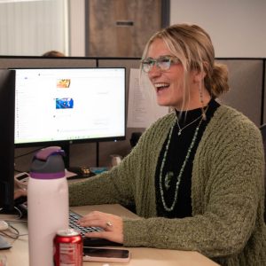 Smiling woman working at computer in office cubicle.
