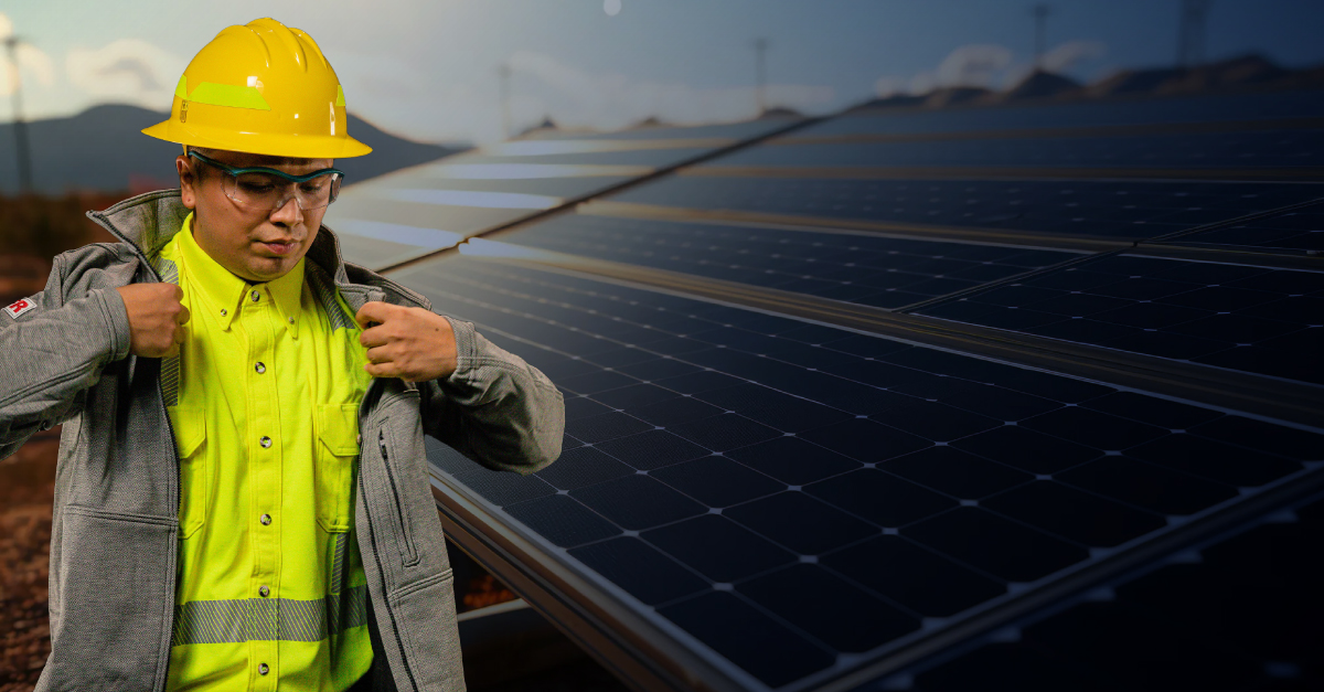 Worker protected by Lakeland FIRE + SAFETY PPE walking past a large solar panel array.