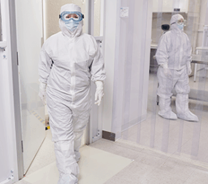 Scientists in protective suits in laboratory setting.